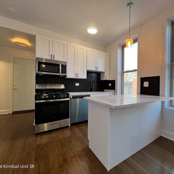 a kitchen with a white island and stainless steel appliances.