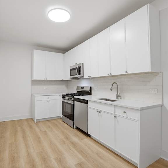 a kitchen with white cabinets and a wooden floor.