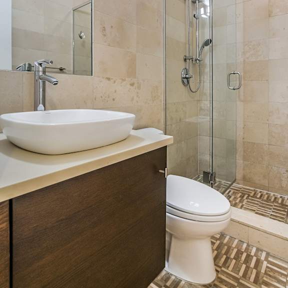 a bathroom with a white sink, toilet, and a glass shower stall.