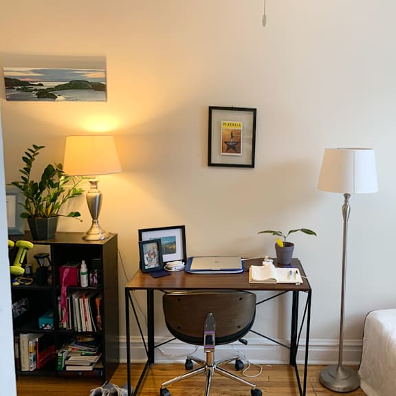 a room with a bed, desk, chair, and a lamp.