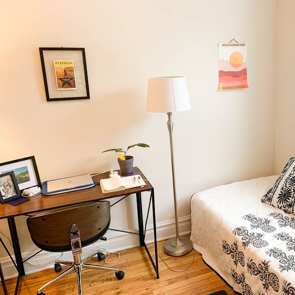 a bedroom with a bed, desk, chair, and pictures on the wall.