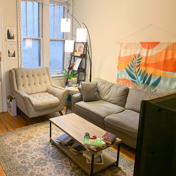 a living room with a grey couch, a white chair, and a coffee table.
