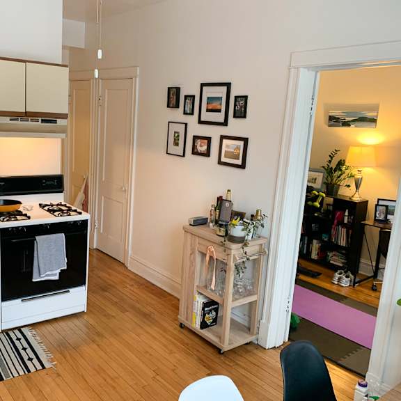 a kitchen with a white oven and microwave, a wooden floor, and a white chair.