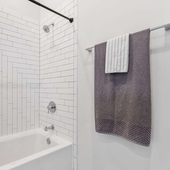 a bathroom with white european tile and a white bathtub