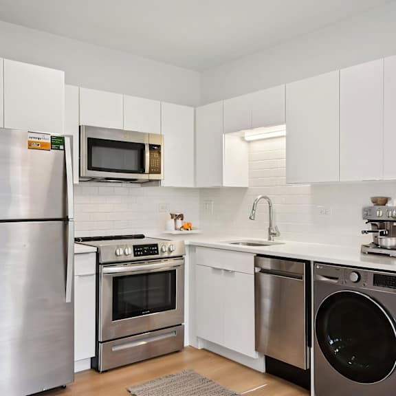 a modern kitchen with a stainless steel refrigerator, microwave, oven, dishwasher, and sink.