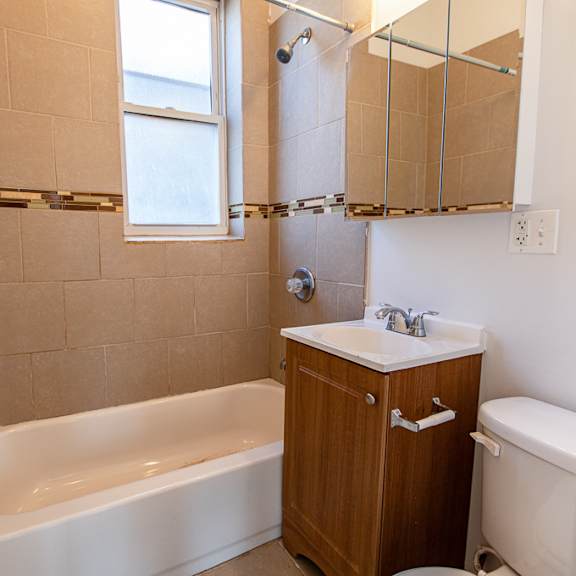 a white bathtub sits in a bathroom with a wooden cabinet and a window.