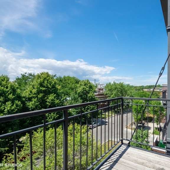 a balcony with a view of trees and a blue sky