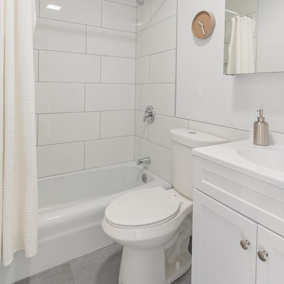 a bathroom with white tiles and a white sink and toilet