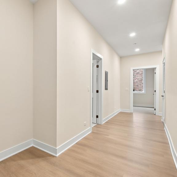 a long hallway with wood floors and white walls.