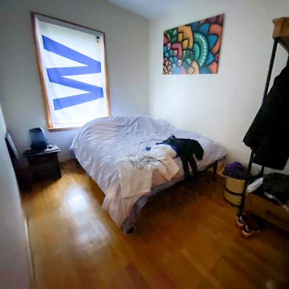 a bedroom with a bed, a wardrobe, and a painting on the wall.