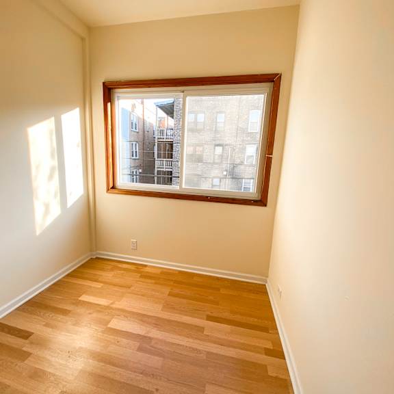 a room with a window and wooden flooring.