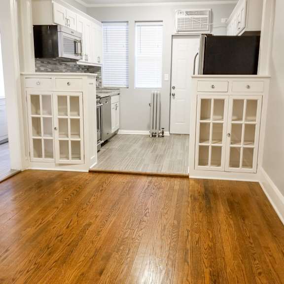 a kitchen with white cabinets and a wooden floor.