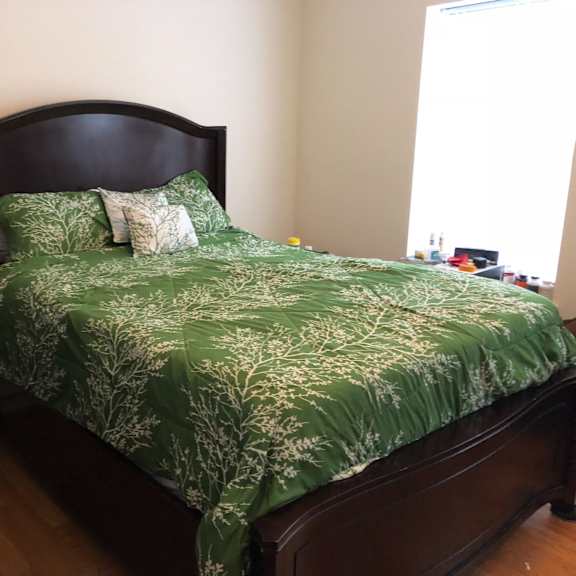 a bedroom with a bed with a green comforter and pillows