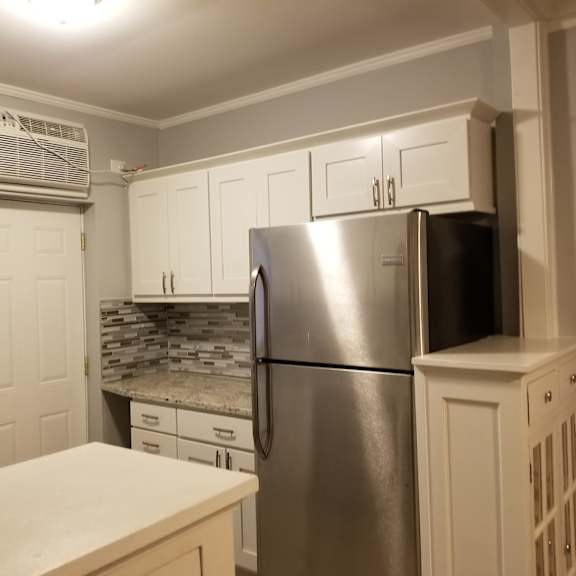 a kitchen with a stainless steel refrigerator and white cabinets.