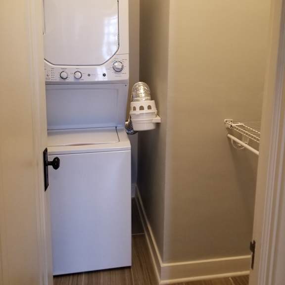 a white dishwasher is in a narrow hallway next to a white towel rack.