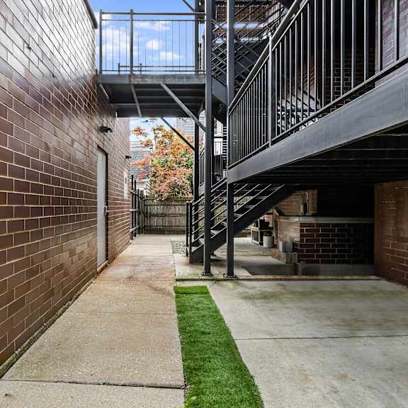a long, narrow walkway with a metal railing on one side and a brick wall on the other.