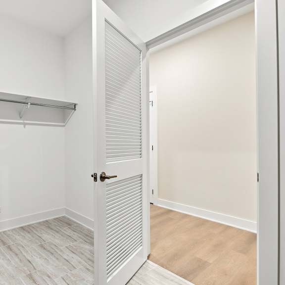 a white closet with a shelf and a door.