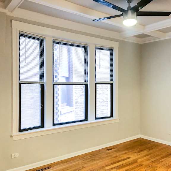 an empty room with three windows and a ceiling fan