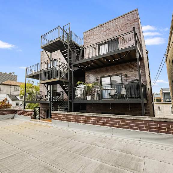 a large open patio area with a metal staircase leading to a balcony.