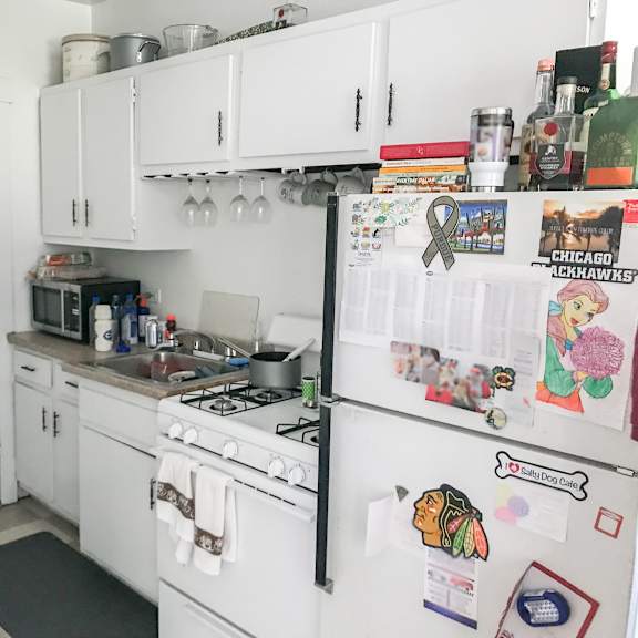 a kitchen with white appliances and a refrigerator covered in magnets and decorations.