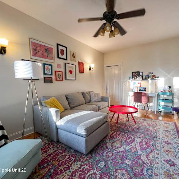 a living room with a grey couch and a red table.