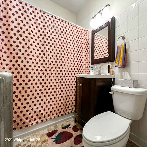 a bathroom with a toilet, sink, and shower curtain.