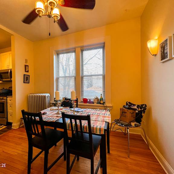 a dining room with a table set for two and a fan on the ceiling.