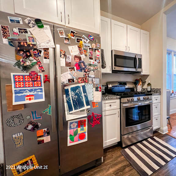 a kitchen with a refrigerator covered in magnets and a striped rug on the floor.