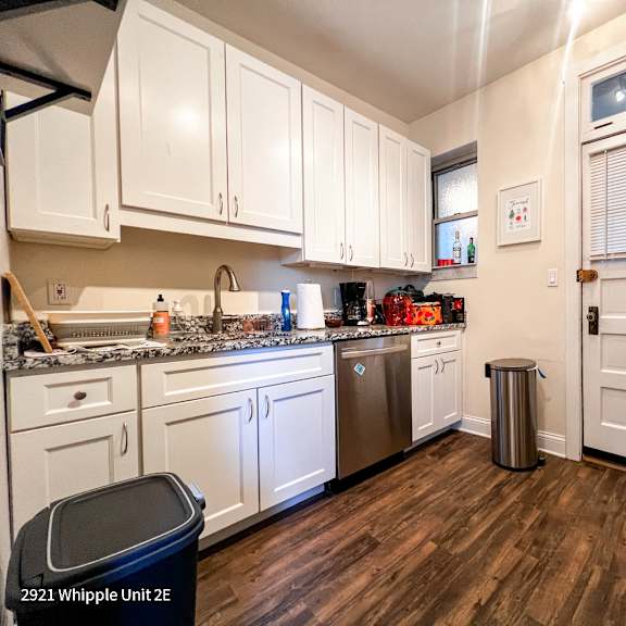a kitchen with white cabinets and a wooden floor.
