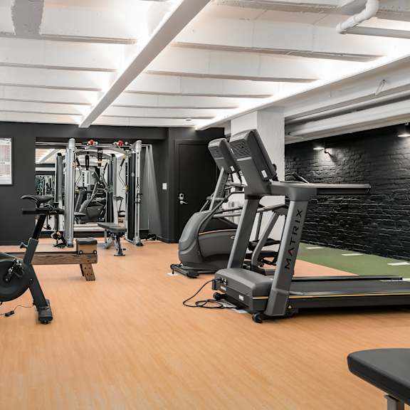 a gym with a variety of equipment including a rowing machine, a bench press, and a leg press.