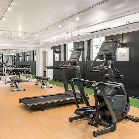 a gym with a variety of equipment including treadmills, weights, and exercise machines.