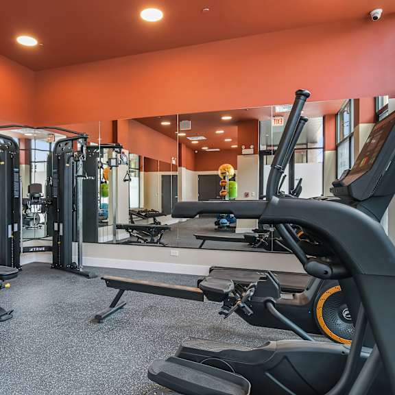 a gym with a variety of equipment including treadmills, weights, and exercise machines.