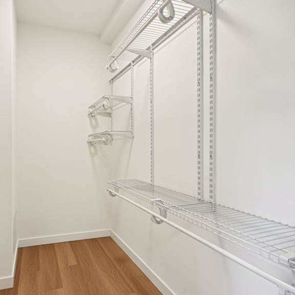 a white door is open to a hallway with a shelving unit on the wall.