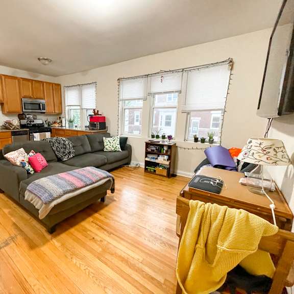 a living room with a grey couch and a yellow blanket on a chair.