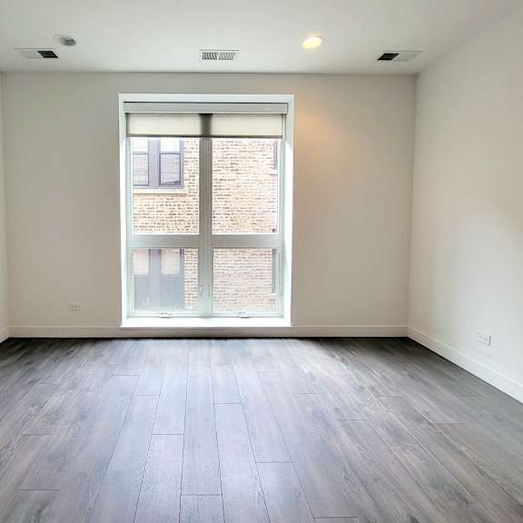 an empty living room with a large window and wood flooring