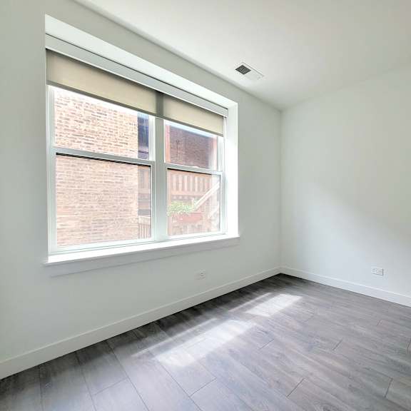 an empty room with wood floors and a window