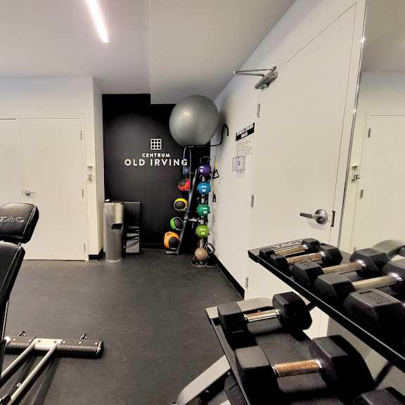 a gym with cardio machines and weights on the floor and a wall with a sign