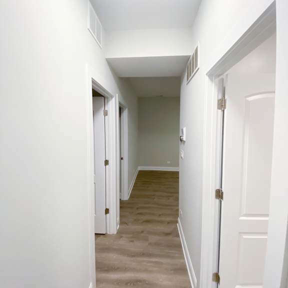 a long hallway with white doors and a tan carpet.