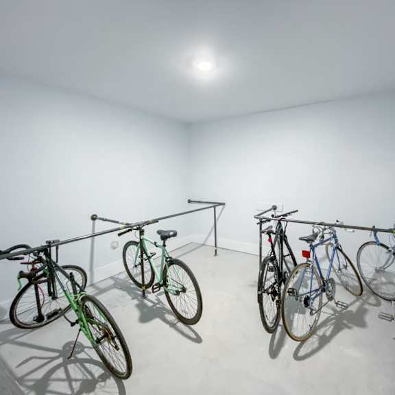 three bicycles are parked in a white room.