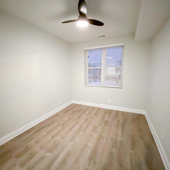 a room with a ceiling fan and a window with blinds.