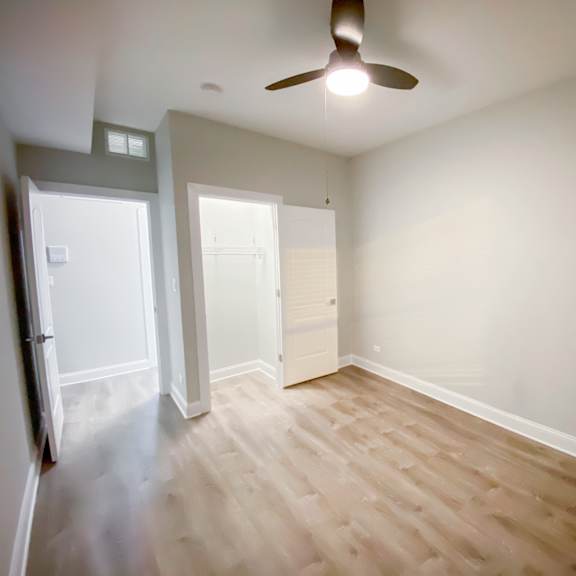 a room with a ceiling fan and wooden flooring.