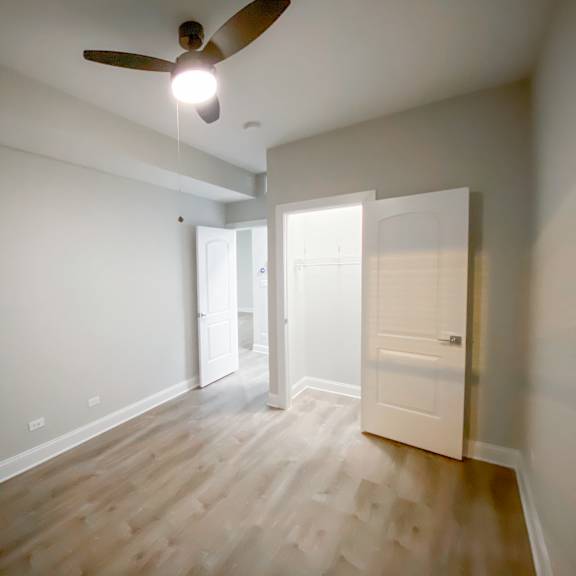 a room with a ceiling fan and wooden flooring.
