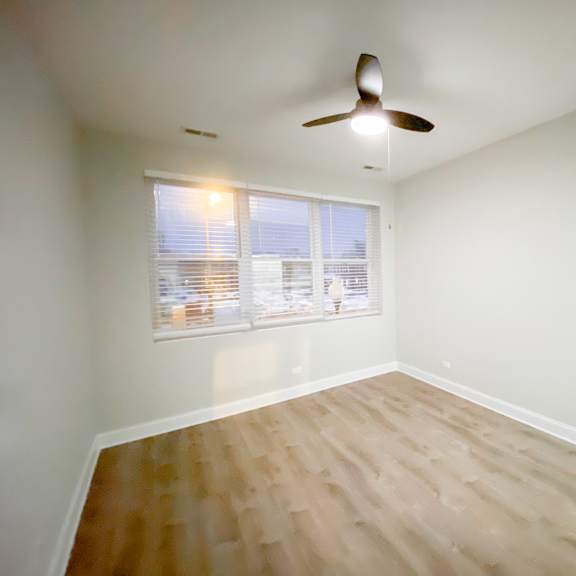 a room with a ceiling fan and wooden flooring.