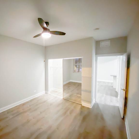 a room with a ceiling fan and wooden flooring.