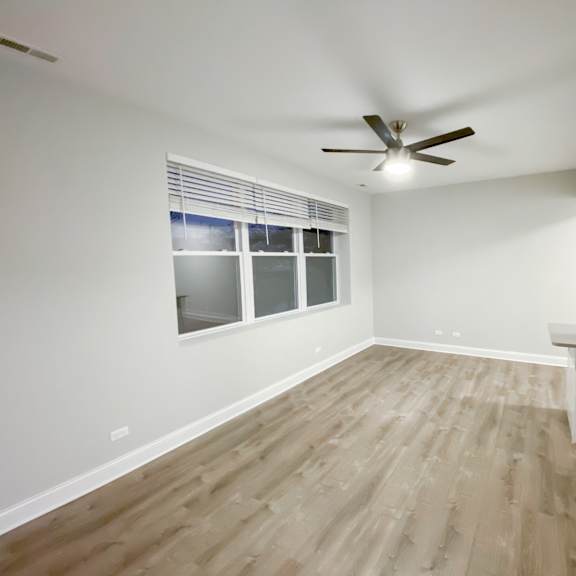a room with a ceiling fan and wooden flooring.