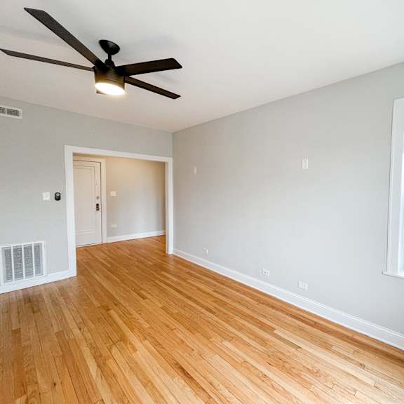 an empty living room with wood floors and a ceiling fan