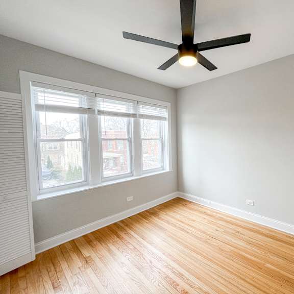 an empty room with wood floors and a ceiling fan