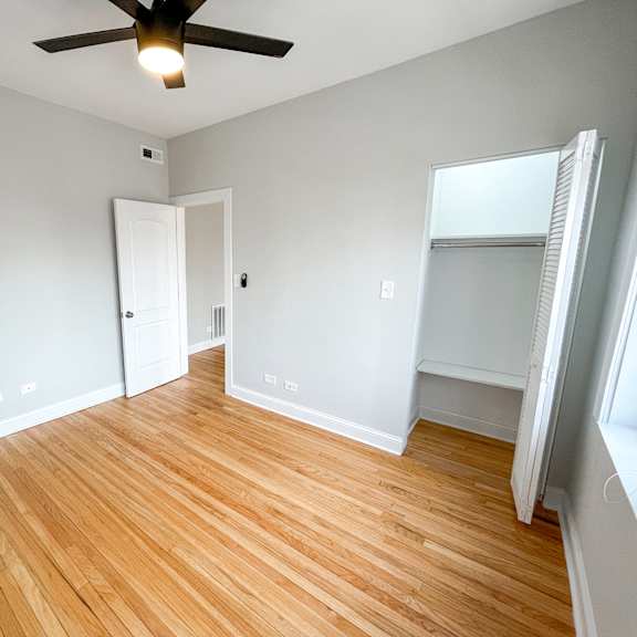 an empty living room with wood flooring and a ceiling fan