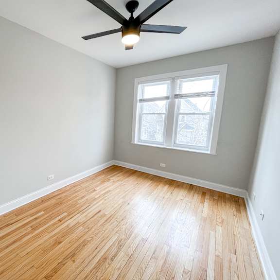 an empty room with wood floors and a ceiling fan