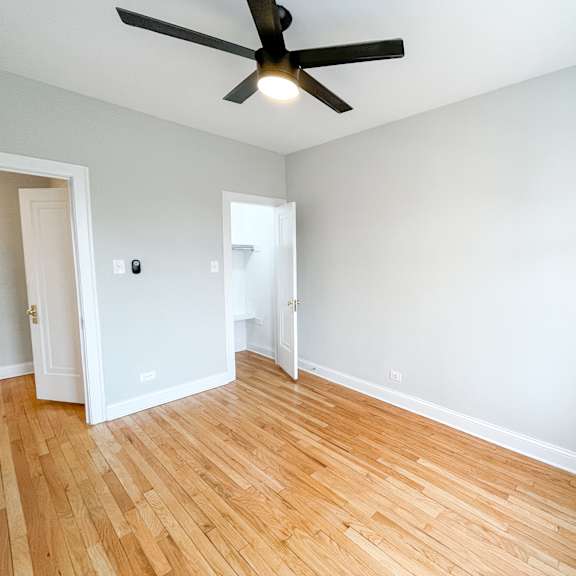 an empty living room with wood floors and a ceiling fan